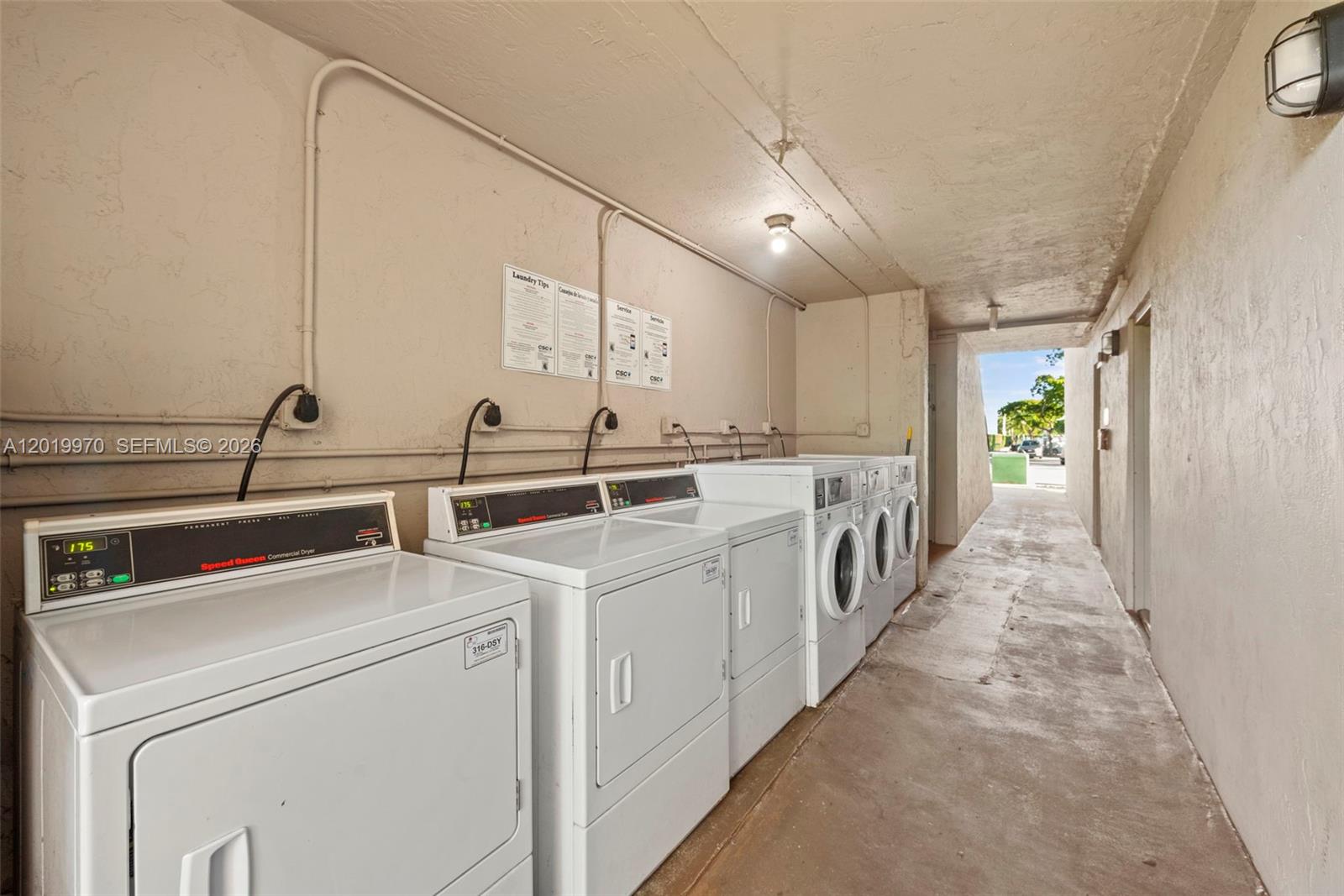 An outdoor laundry area features multiple white commercial dryers lined up against a beige wall — 3581 SW 117th Ave # 206, Miami FL 33175, MIAMI, FL