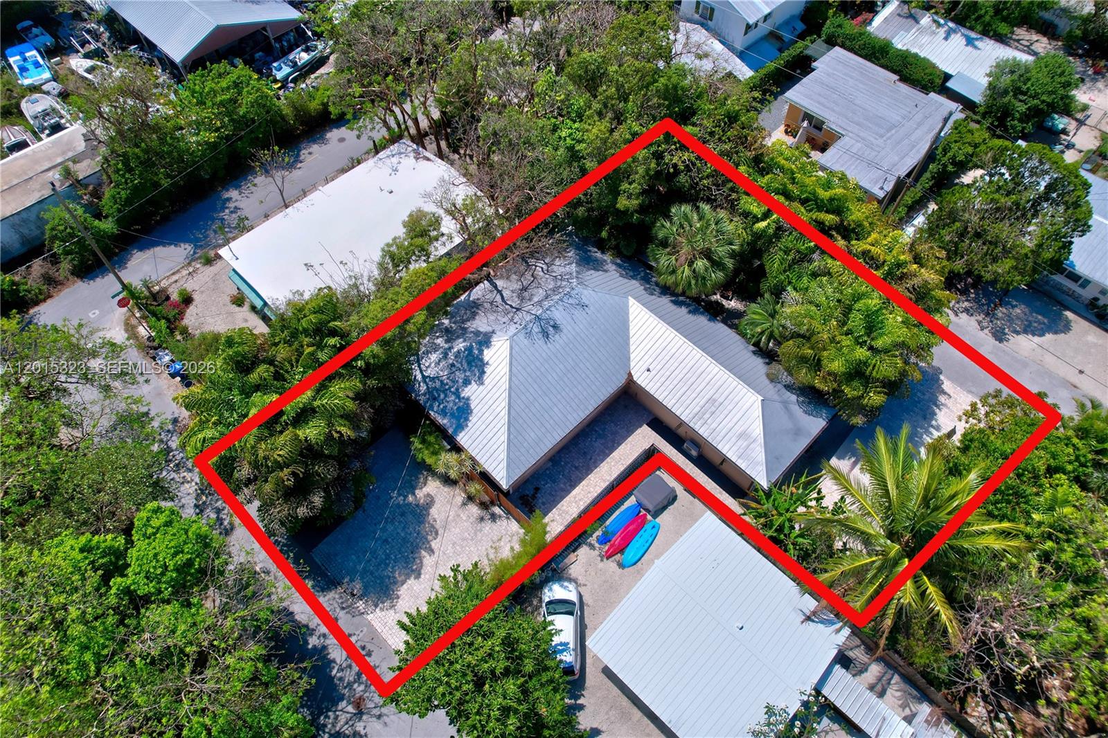 An aerial view shows an L-shaped house with a metal roof and a paved driveway — 85 Henry Morgan Dr, Key Largo FL 33037, KEY LARGO, FL