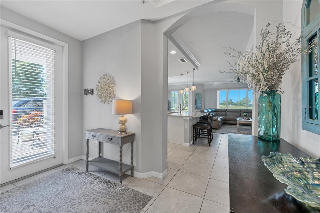 An entryway with a console table leads into an open-concept kitchen and living area — 7564 DIVOT LOOP, BRADENTON, FL