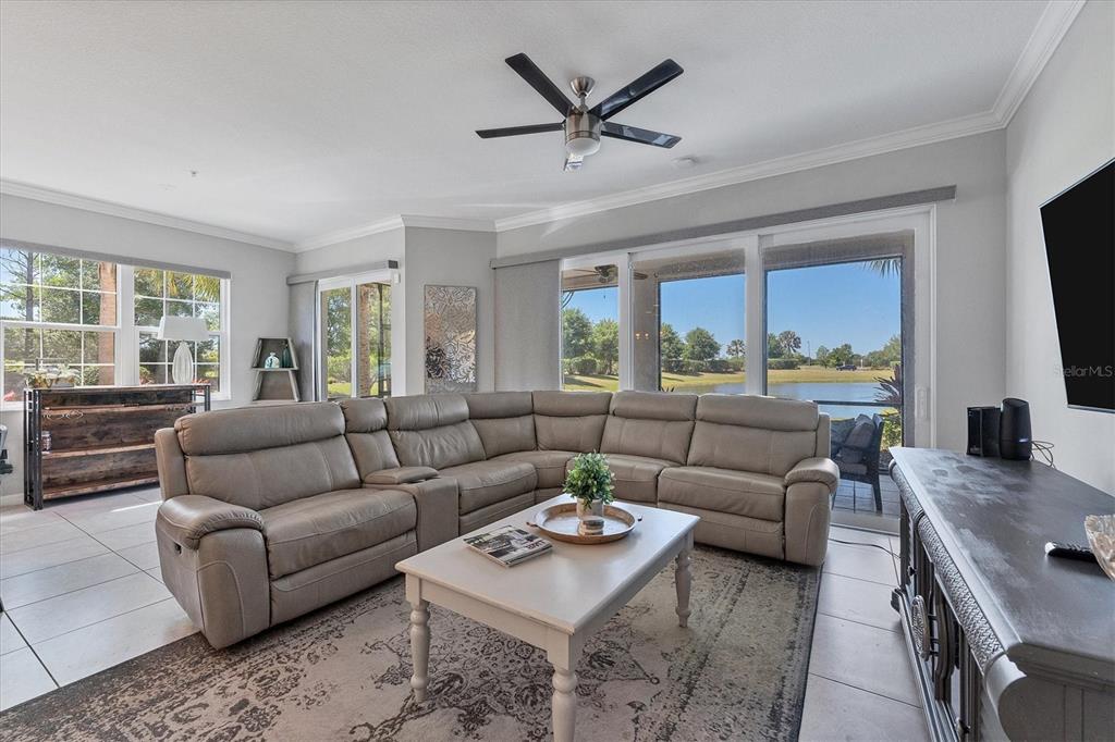 A living room features a large sectional sofa, a coffee table, and sliding glass doors — 7564 DIVOT LOOP, BRADENTON, FL