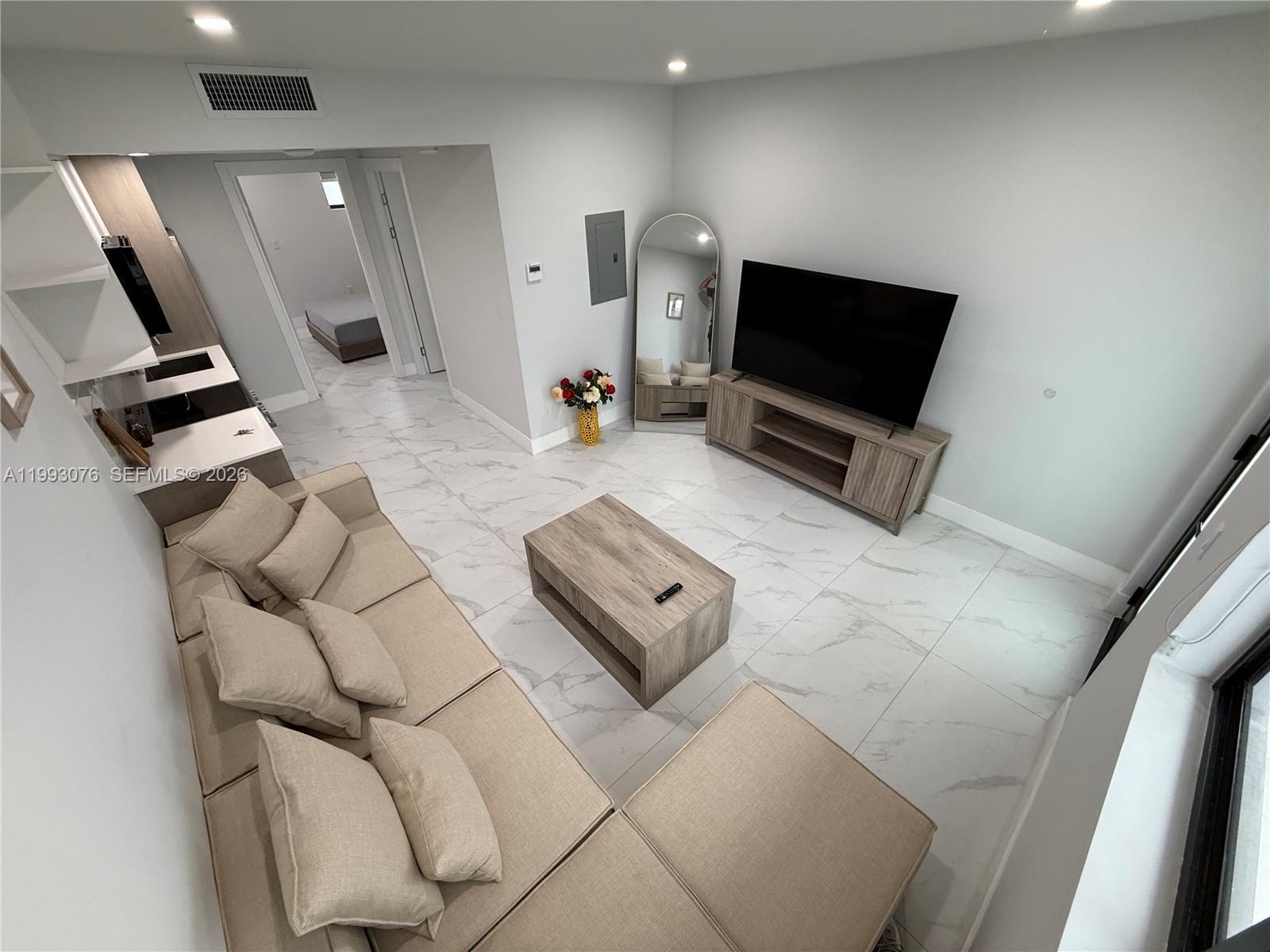 A living room features a beige sectional sofa, a wooden coffee table, and marble flooring — 944 Jefferson Ave # 15, Miami Beach FL 33139, MIAMI BEACH, FL