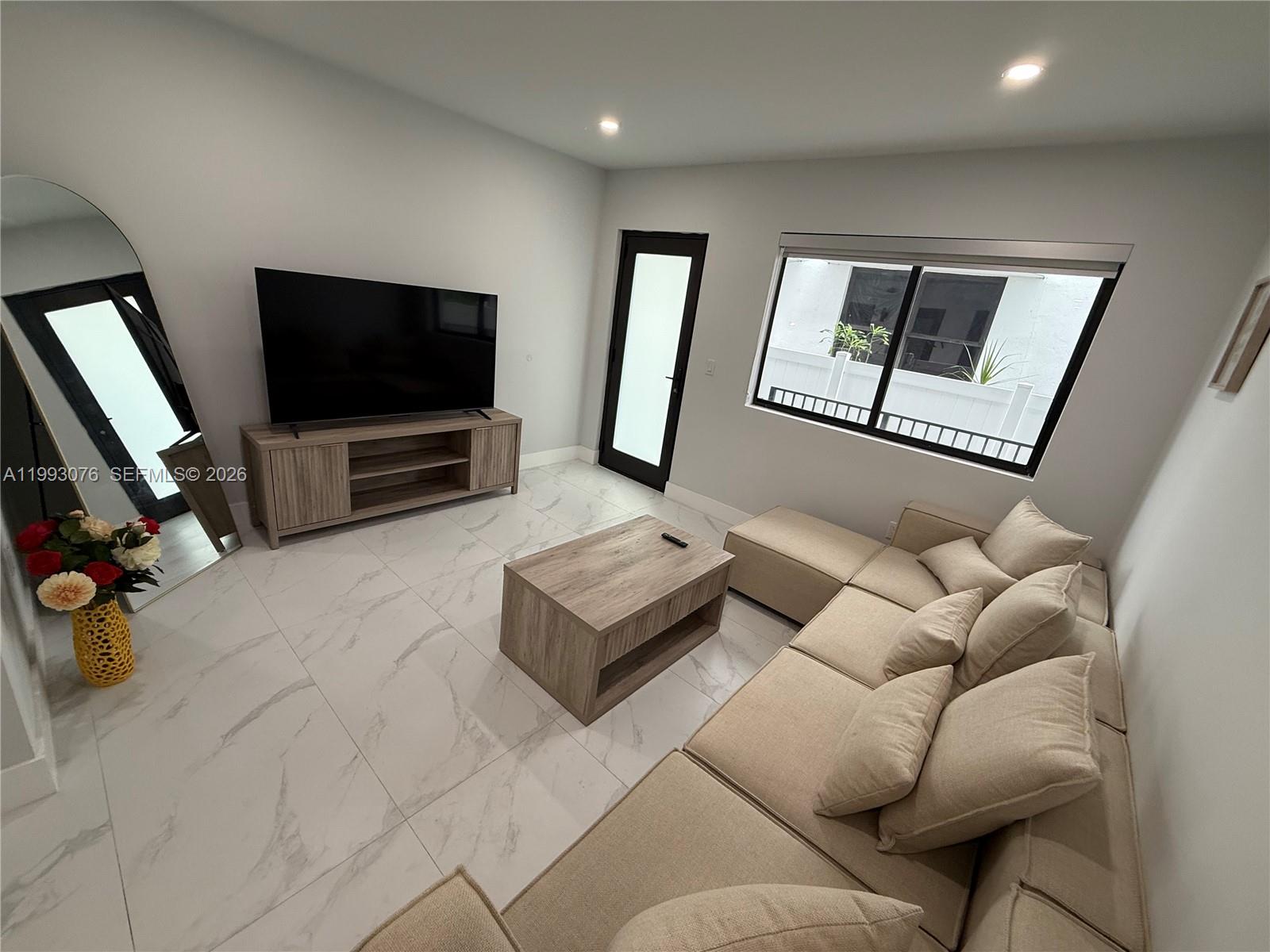 A living room features light tile flooring, a beige sectional sofa, and a wood media console — 944 Jefferson Ave # 15, Miami Beach FL 33139, MIAMI BEACH, FL