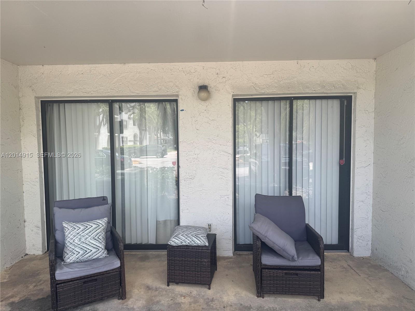 A covered patio features two wicker chairs, a small side table, and sliding glass doors — 520 S Park Rd # 12, Hollywood FL 33021, HOLLYWOOD, FL
