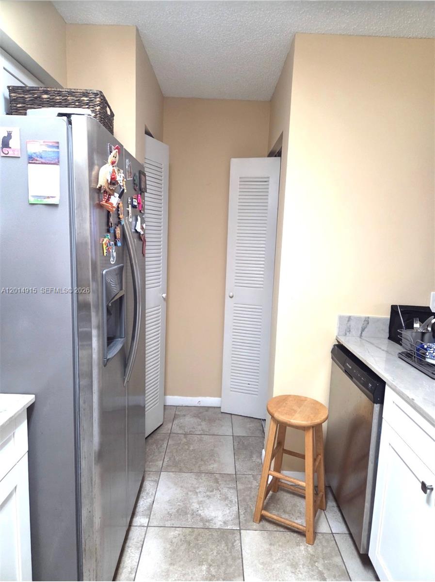 A kitchen features a stainless steel refrigerator, a dishwasher, and two white louvered doors — 520 S Park Rd # 12, Hollywood FL 33021, HOLLYWOOD, FL