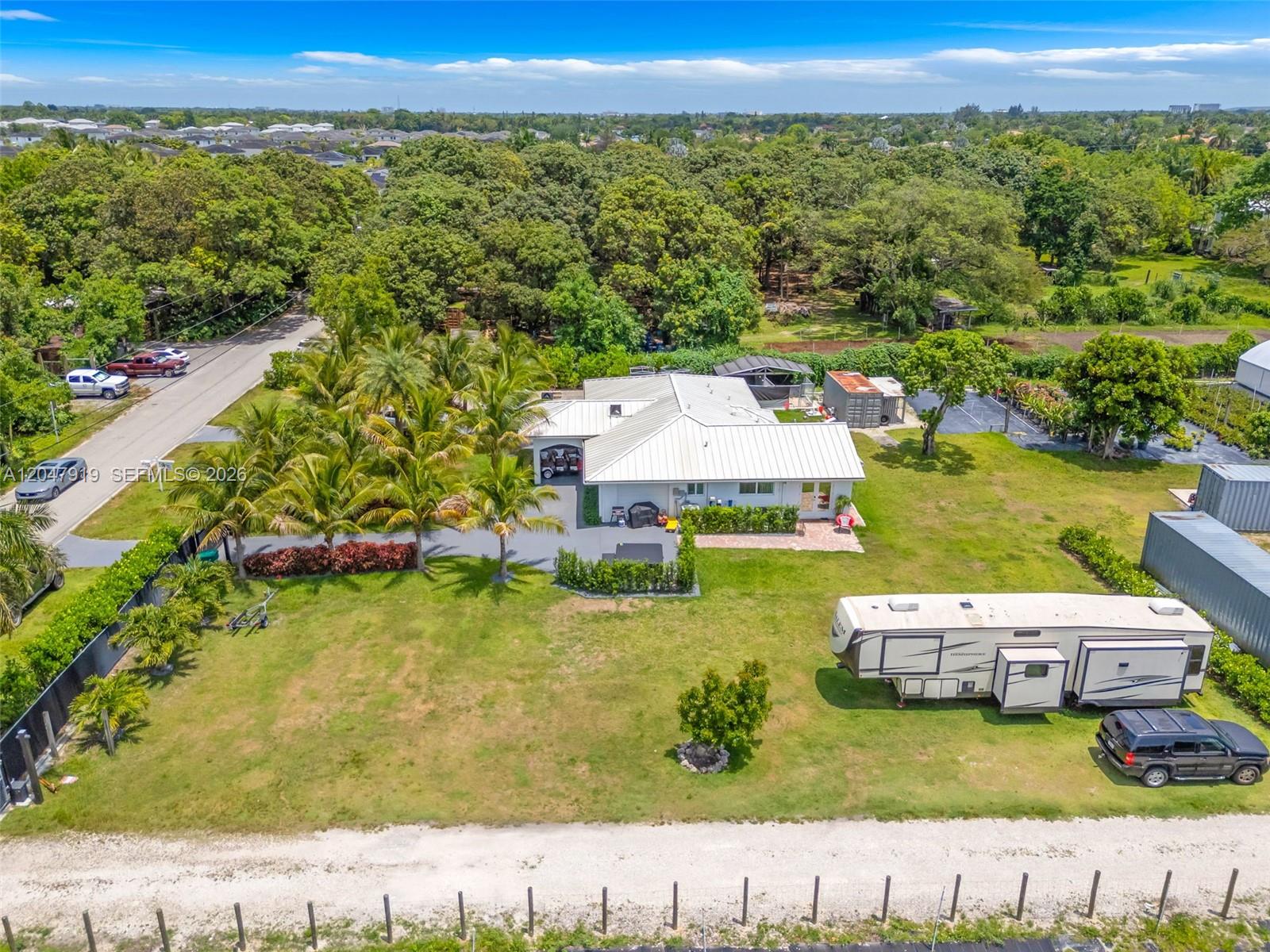 An aerial view shows a house with a metal roof, palm trees, and a parked RV — 13770 SW 192nd St, Miami FL 33177, MIAMI, FL