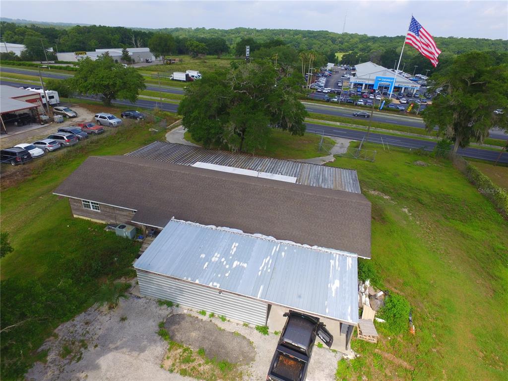 An aerial view shows a building with a metal roof and a large American flag — 10736 US HIGHWAY 301, DADE CITY, FL