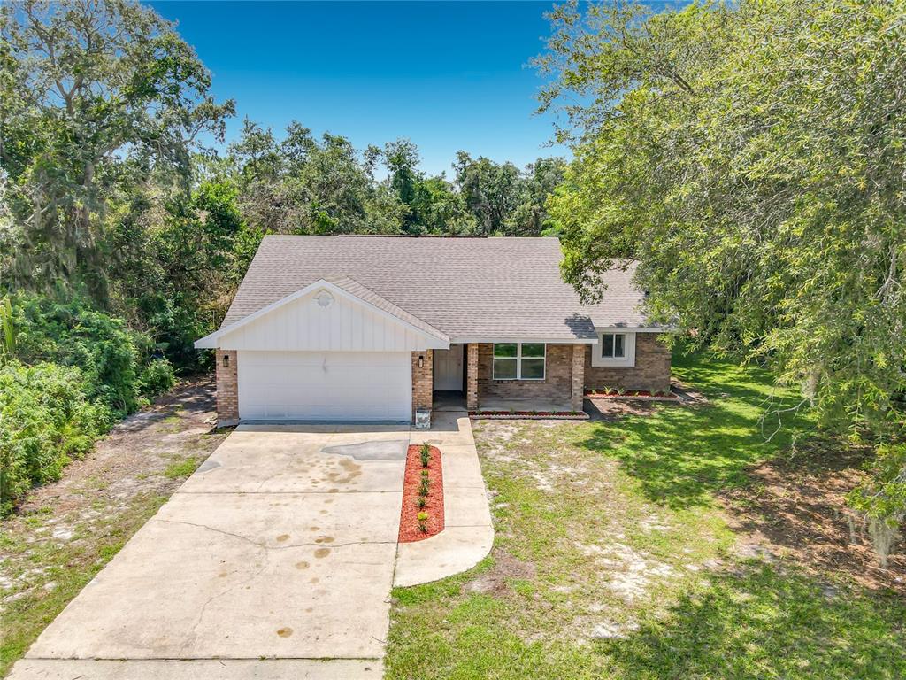 An aerial view of a single-story brick house with a white garage and concrete driveway — 1483 TIVOLI DRIVE, DELTONA, FL
