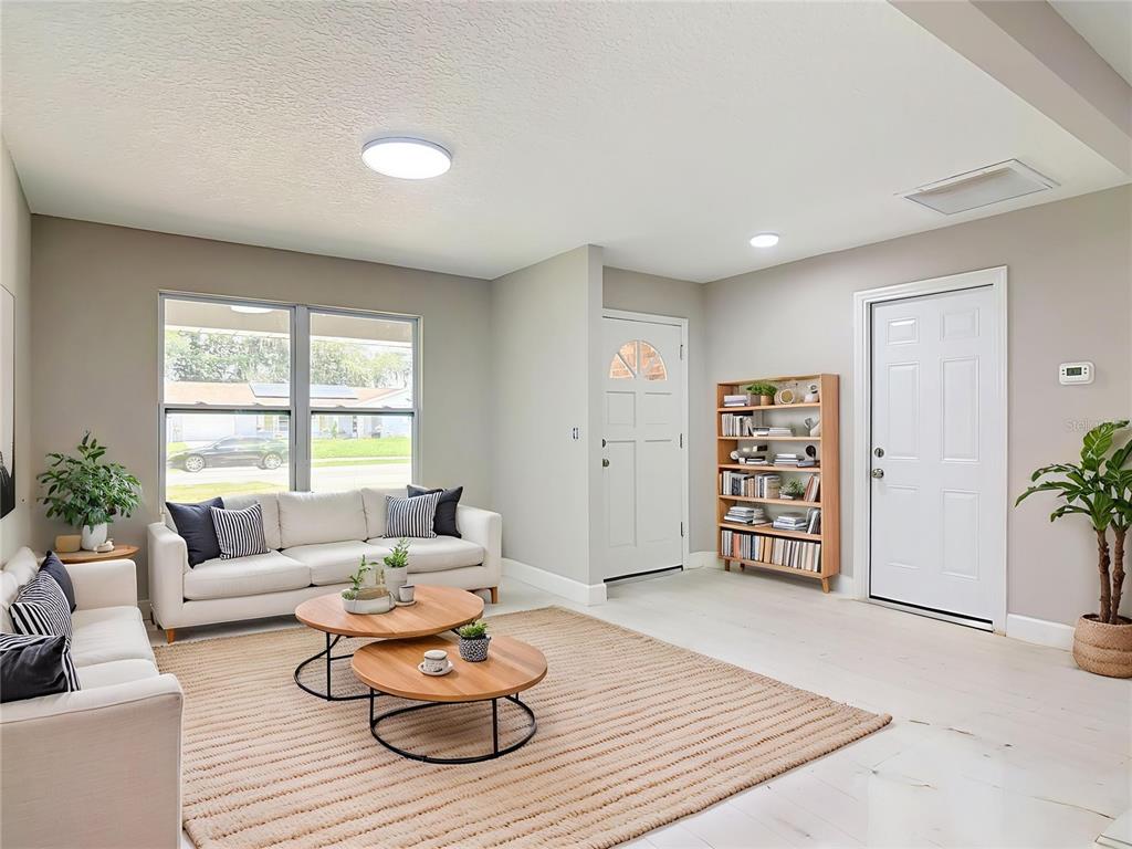 A living room features a white sofa, two round coffee tables, and a bookshelf — 1483 TIVOLI DRIVE, DELTONA, FL