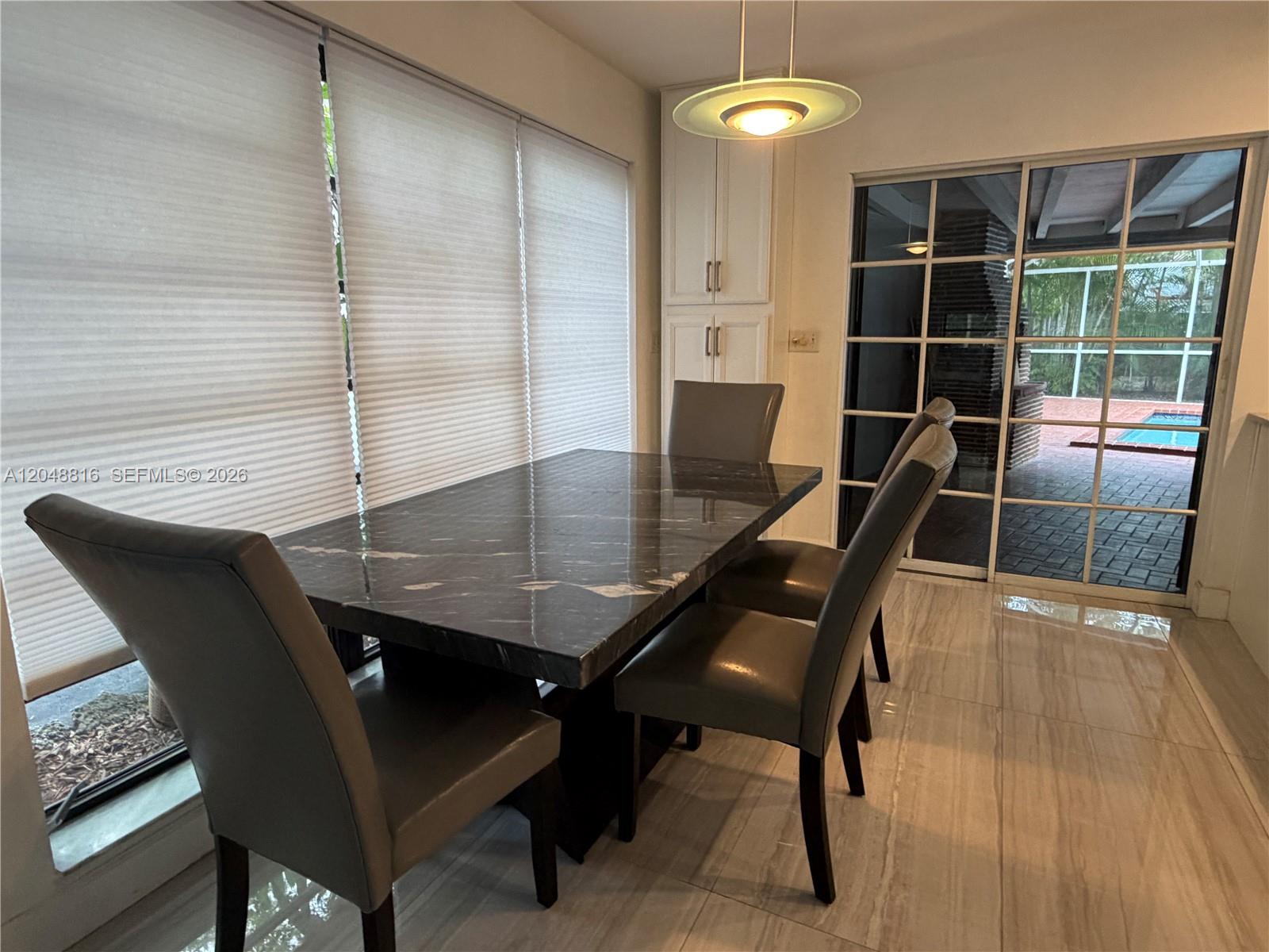 A dining area features a dark marble table, gray chairs, and a sliding glass door — 13200 SW 83rd Ave, Pinecrest FL 33156, PINECREST, FL