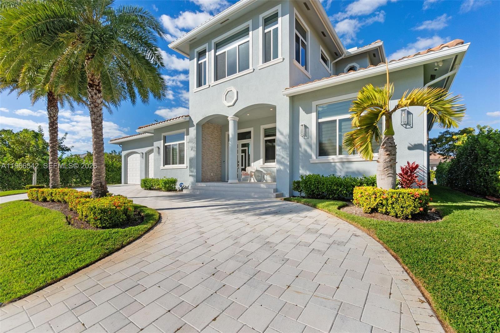 A two-story light blue house features a paved driveway, palm trees, and a covered entryway — 1070 Dana CT, Marco Island FL 34145, MARCO ISLAND, FL