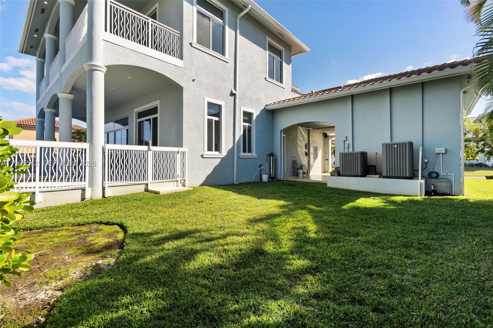 The exterior of a two-story house features a grassy lawn, a patio, and HVAC units — 1070 Dana CT, Marco Island FL 34145, MARCO ISLAND, FL