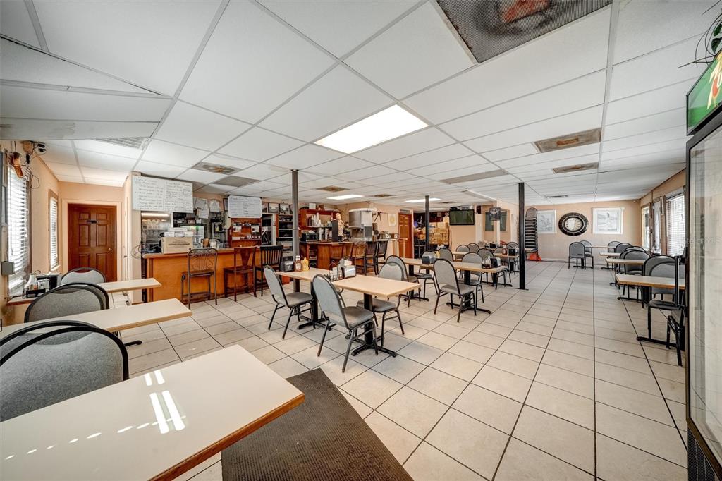 A restaurant interior features tables, chairs, a service counter, and a drop ceiling — 5202 N NEBRASKA AVENUE E, TAMPA, FL