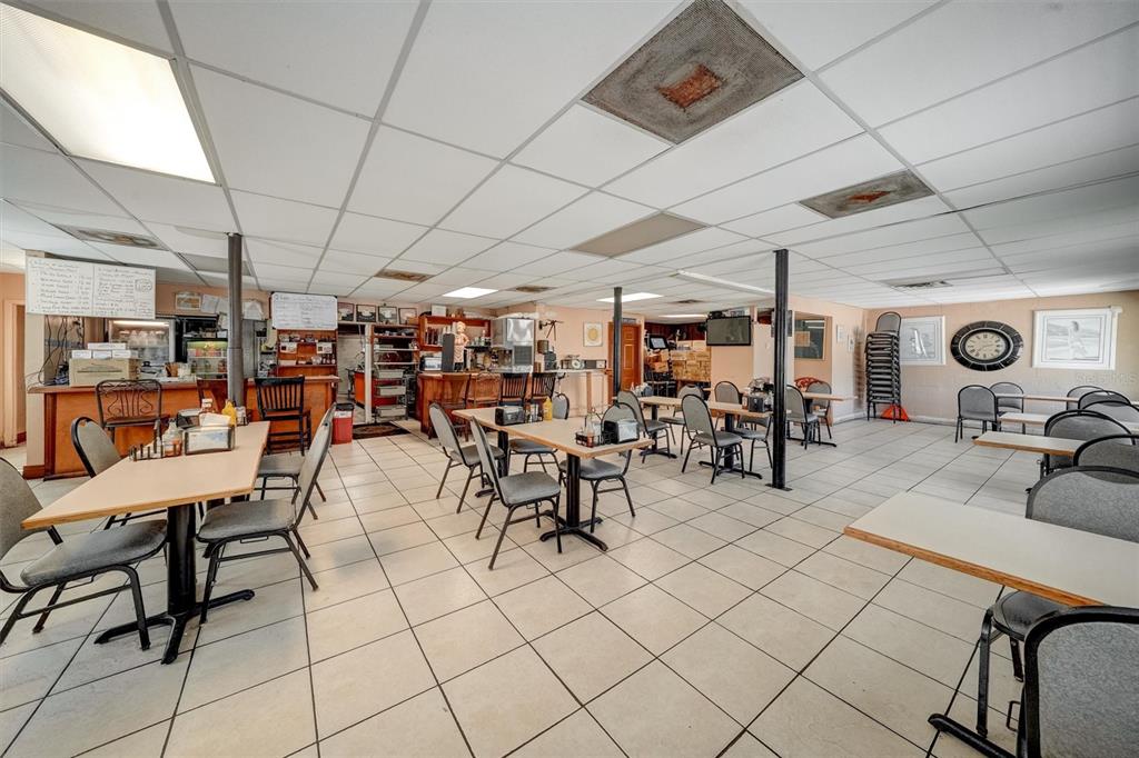 A restaurant dining area features multiple tables, chairs, a service counter, and a drop ceiling — 5202 N NEBRASKA AVENUE E, TAMPA, FL