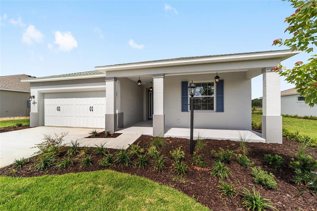 A single-story house with a two-car garage, covered porch, and blue shutters — 10394 SW 107TH COURT, OCALA, FL
