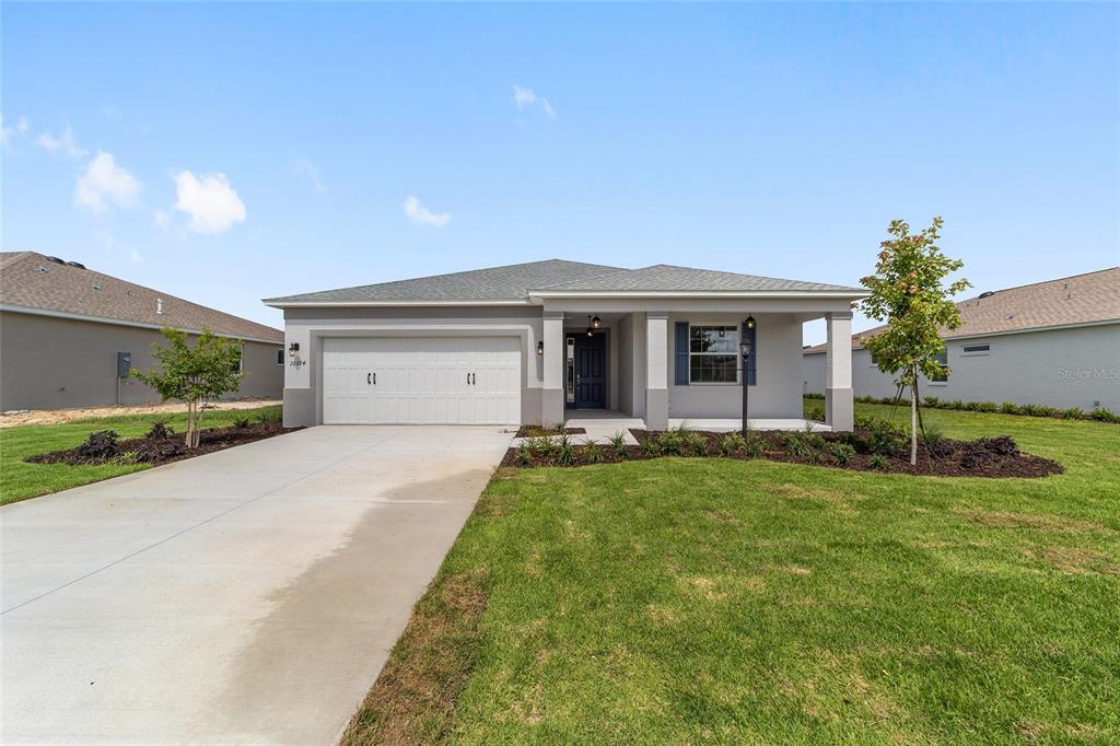 A single-story suburban house with a two-car garage, gray exterior, and a front porch — 10394 SW 107TH COURT, OCALA, FL