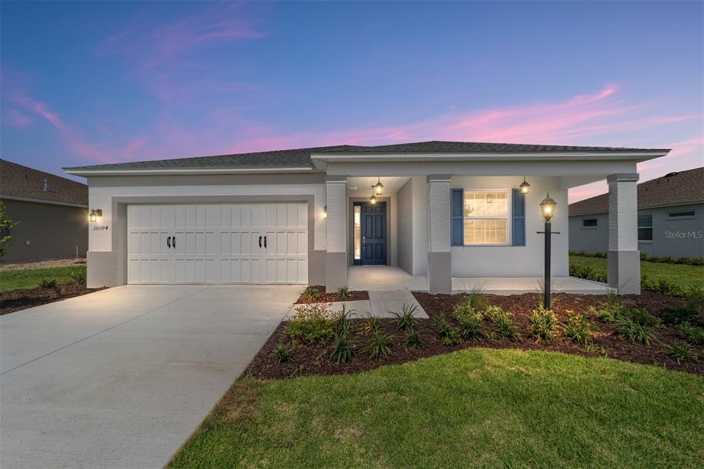 A single-story house exterior features a white garage, a covered porch, and blue shutters — 10394 SW 107TH COURT, OCALA, FL