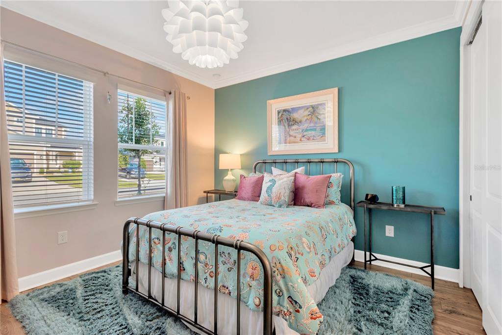 A bedroom features a metal bed frame, teal accent wall, and a shaggy blue rug — 7213 TALAMORE DRIVE, WESLEY CHAPEL, FL