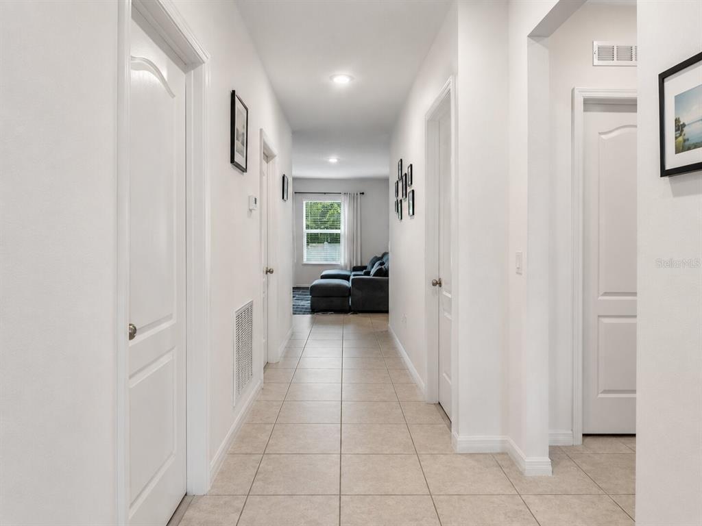 A tiled hallway leads to a living area with a sofa and a window — 626 GILA DRIVE, POINCIANA, FL