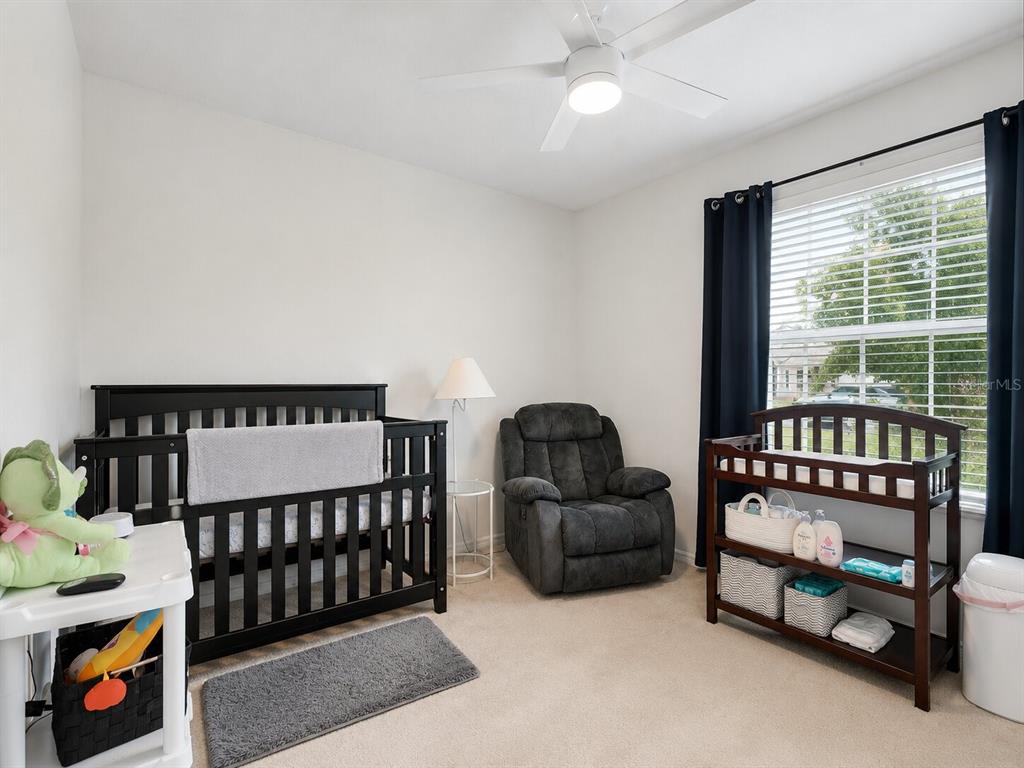 A nursery features a dark wood crib, a matching changing table, and a gray recliner — 626 GILA DRIVE, POINCIANA, FL