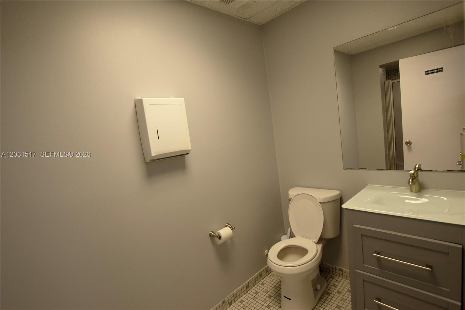 A bathroom features a toilet, a vanity with a sink, and a paper towel dispenser — HOLLYWOOD, FL