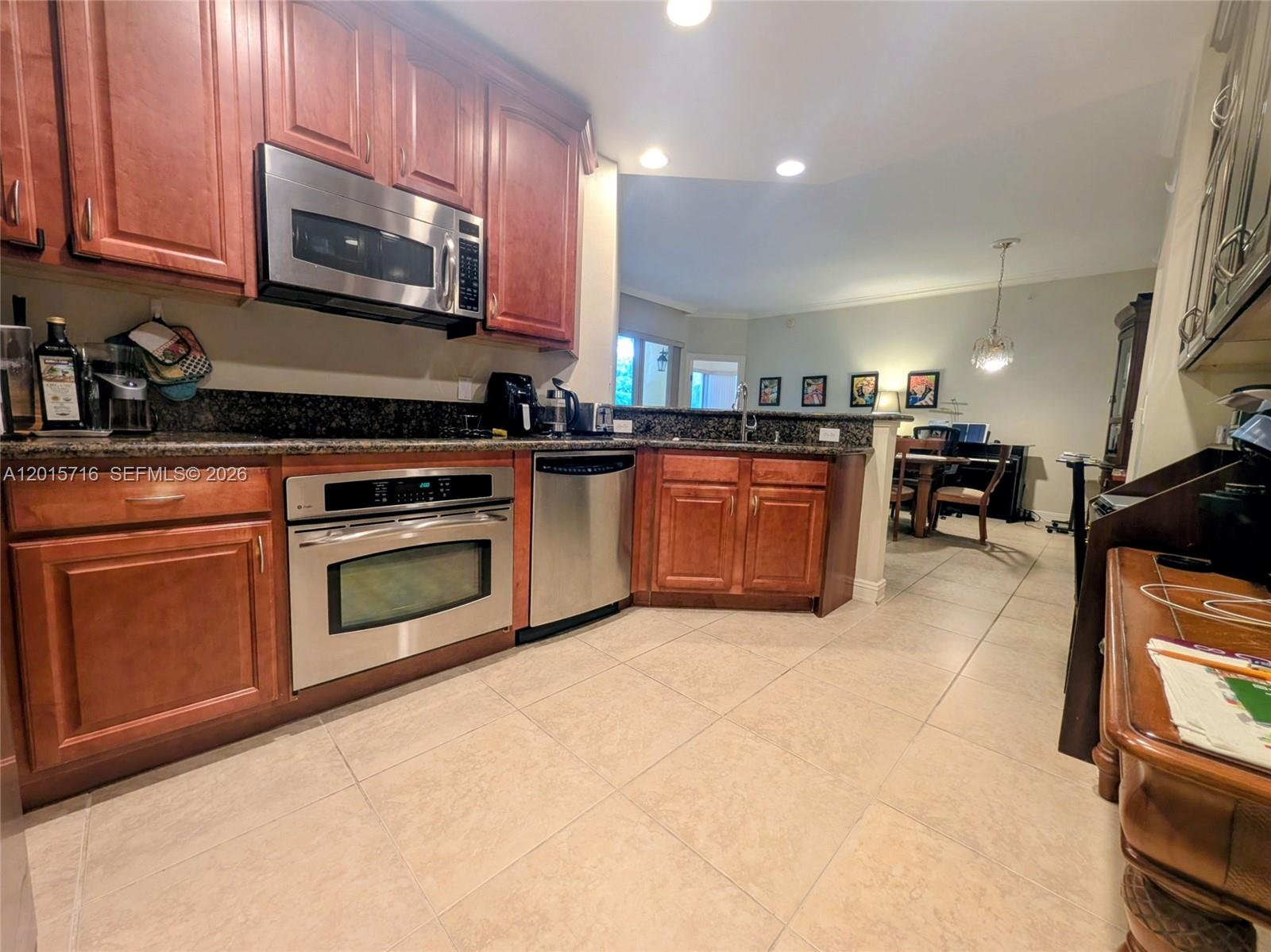 A kitchen features cherry wood cabinets, stainless steel appliances, and granite countertops — 16101 Emerald Estates Dr # 254, Weston FL 33331, WESTON, FL