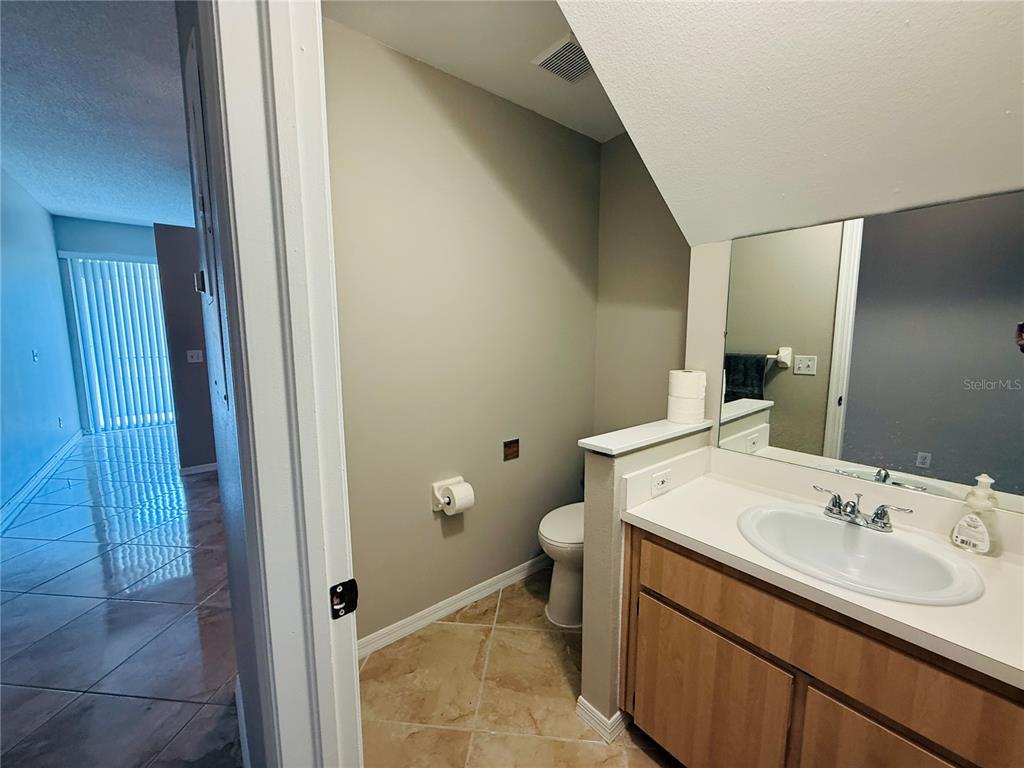 A bathroom features a vanity with a sink, a toilet, and beige tile flooring — 2843 THAXTON DRIVE UNIT 38, PALM HARBOR, FL