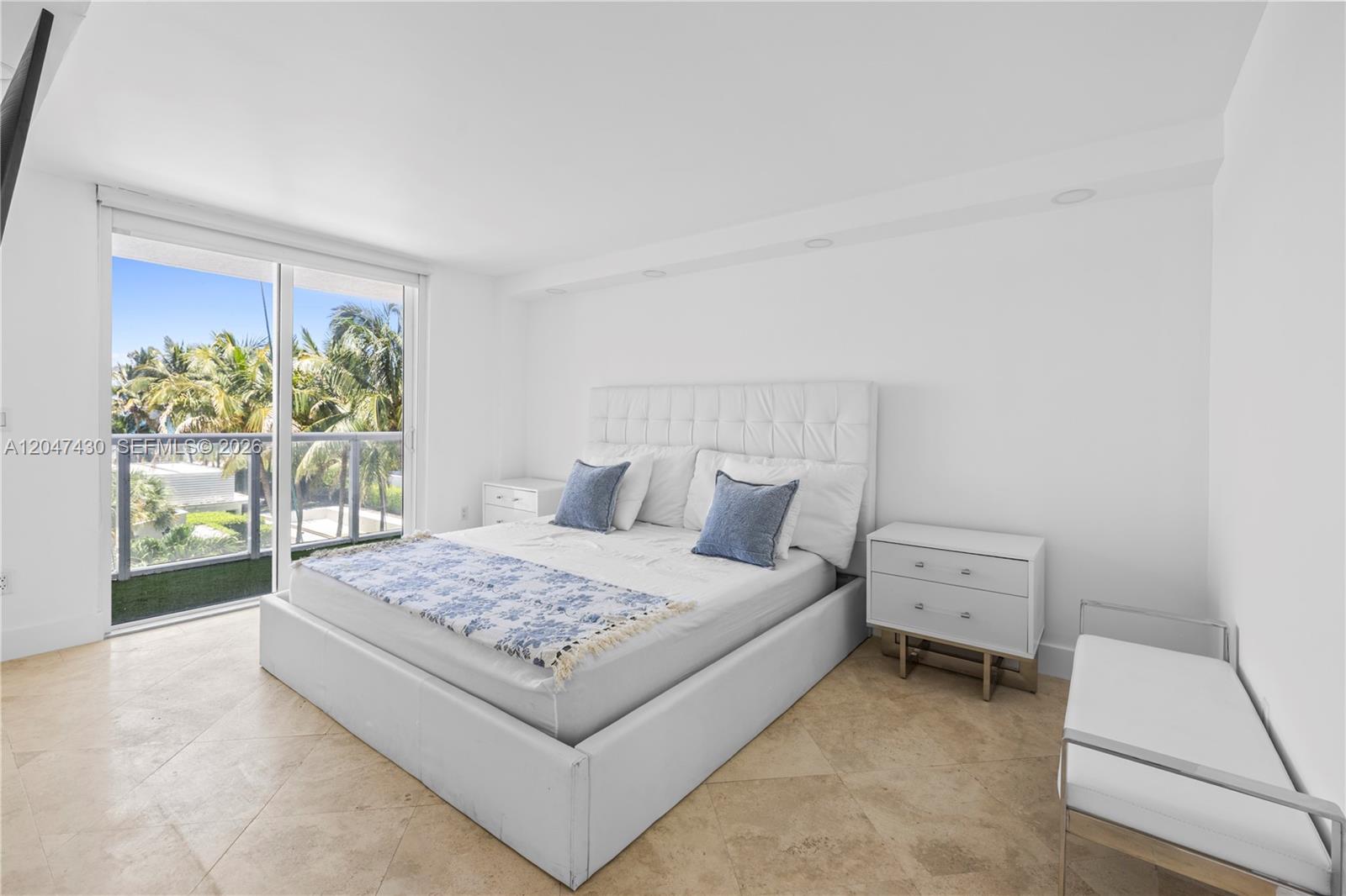 A bedroom features a white tufted bed, two nightstands, and a balcony with palm trees — 2457 Collins Ave # 406, Miami Beach FL 33140, MIAMI BEACH, FL