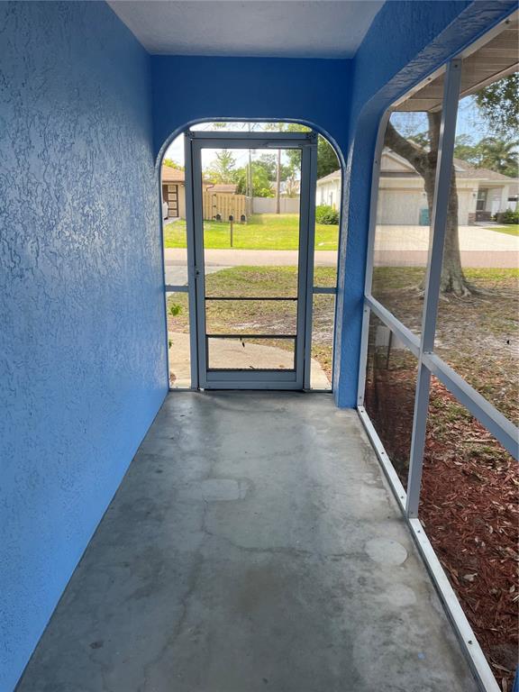 A view from a covered, blue-walled screened porch looking out toward a residential street — 23076 AUGUST AVENUE, PORT CHARLOTTE, FL