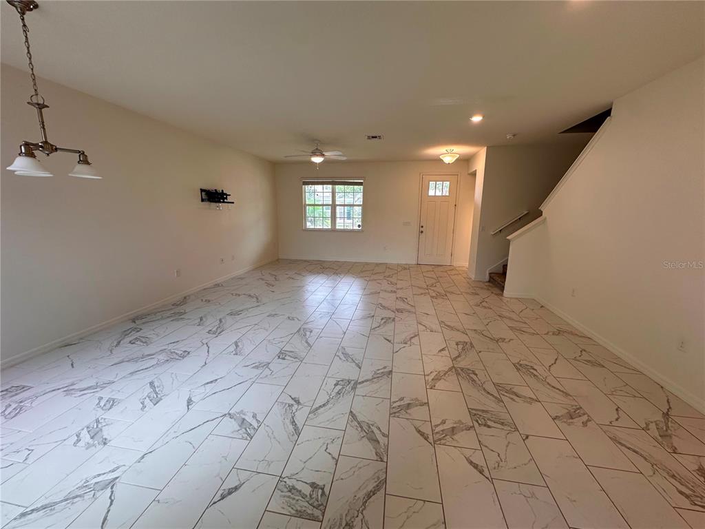 An open-concept living area features white marble-look tile flooring, a ceiling fan, and a staircase — 5844 SOTER LANE, WINDERMERE, FL