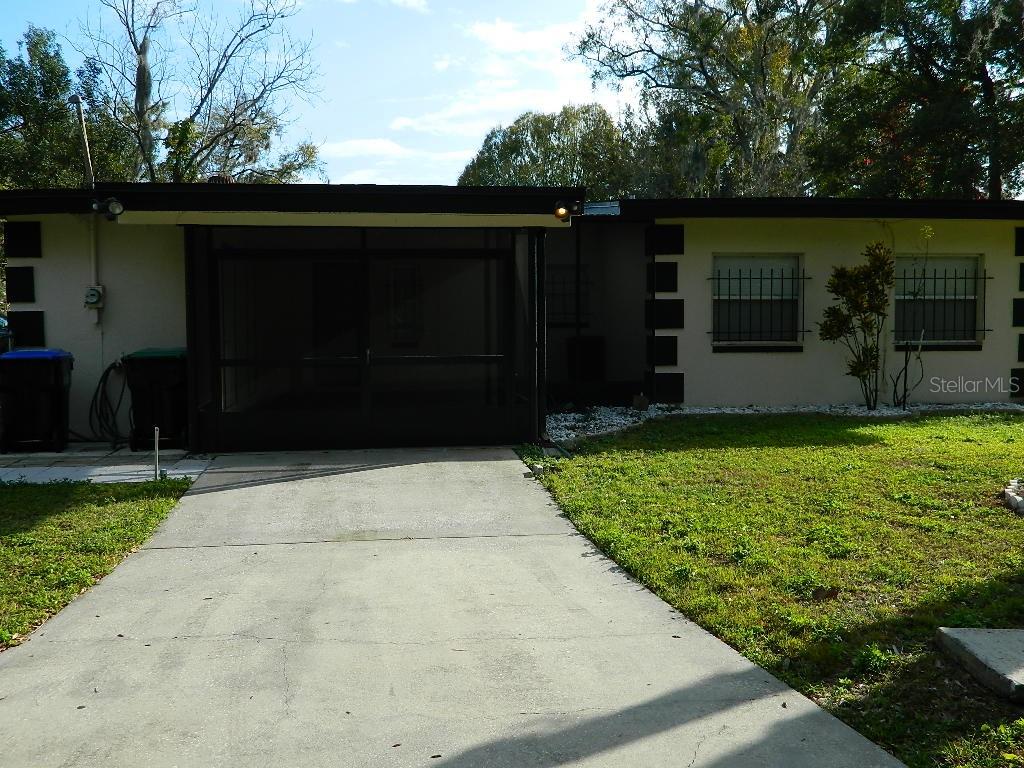 A single-story house with a screened-in porch, concrete driveway, and two windows with security bars — 944 KENSINGTON DRIVE, ORLANDO, FL