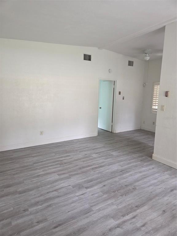 An empty room features white walls, light gray wood-look flooring, and a doorway leading inside — 944 KENSINGTON DRIVE, ORLANDO, FL