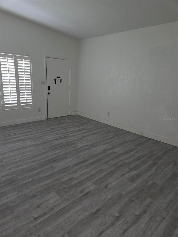 An empty room features gray wood-look flooring, white walls, a window with shutters, and a door — 944 KENSINGTON DRIVE, ORLANDO, FL