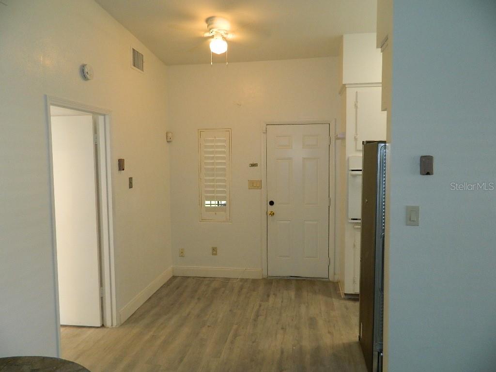 A room with light-colored walls, wood-look flooring, a ceiling fan, and a white entry door — 944 KENSINGTON DRIVE, ORLANDO, FL
