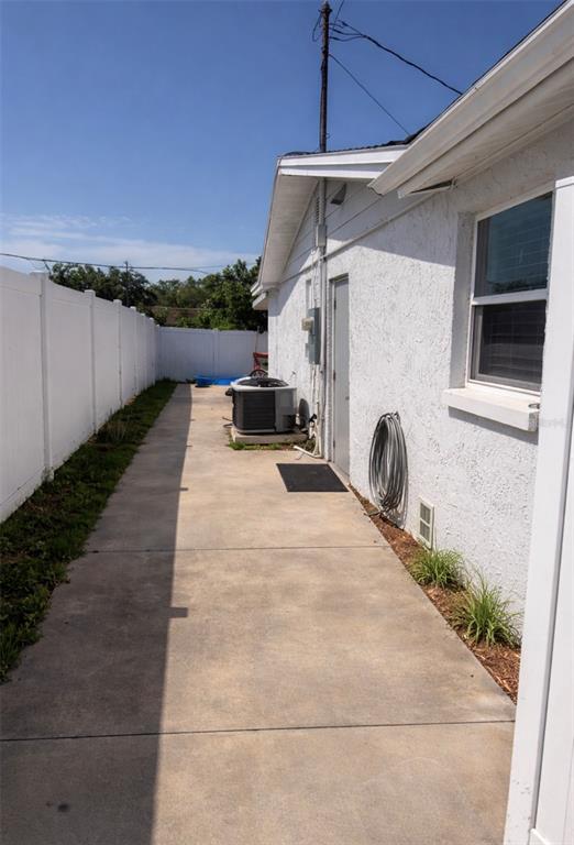 A concrete side yard features a white fence, an HVAC unit, and a hose reel — 5338 TROUBLE CREEK ROAD, NEW PORT RICHEY, FL