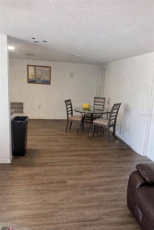 A dining area features a glass-topped table, three chairs, and wood-look flooring — 5338 TROUBLE CREEK ROAD, NEW PORT RICHEY, FL