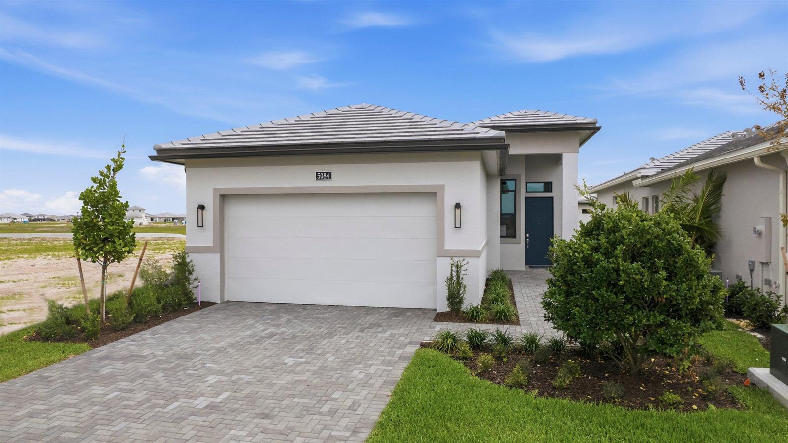 A single-story house with a white stucco facade, a two-car garage, and a paver driveway — 5084 Lido Key Lane, Westlake FL 33470, WESTLAKE, FL