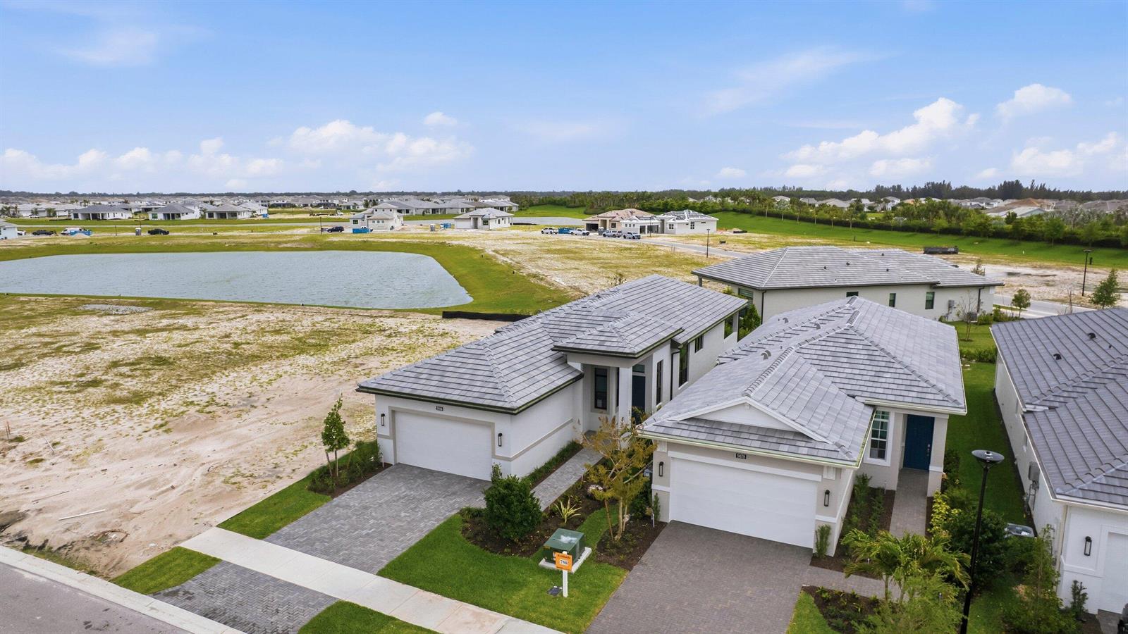 An aerial view shows two modern single-family homes with gray tile roofs and paved driveways — 5084 Lido Key Lane, Westlake FL 33470, WESTLAKE, FL