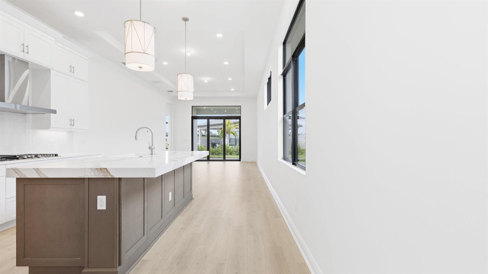 A modern kitchen features a large gray island with a white marble countertop and pendant lights — 5084 Lido Key Lane, Westlake FL 33470, WESTLAKE, FL