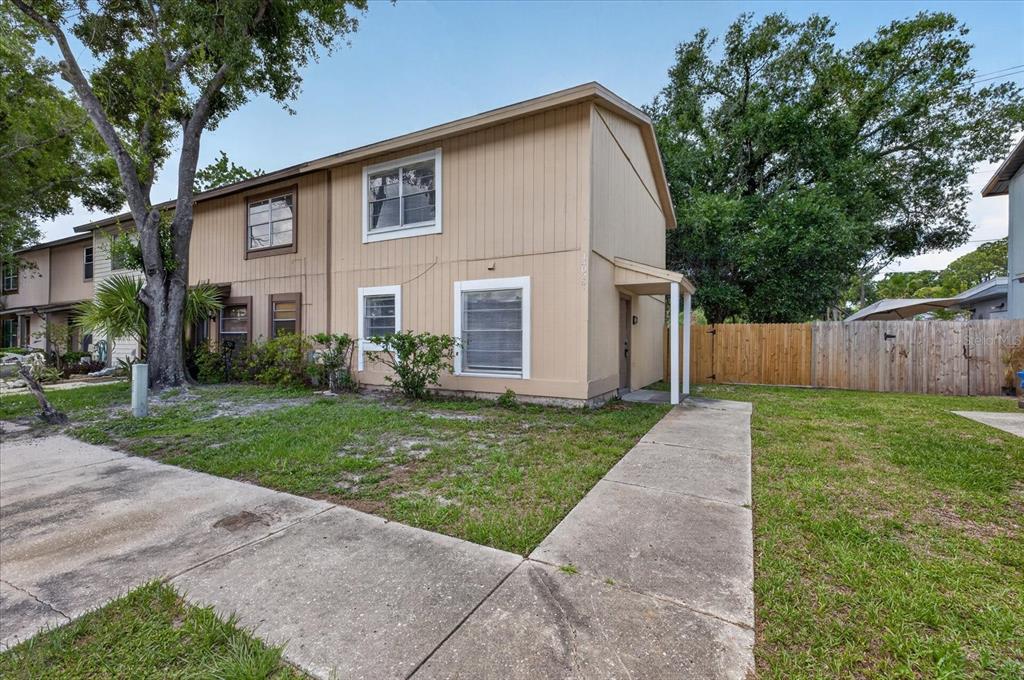 A two-story tan townhouse with a concrete walkway and a wooden privacy fence — 14024 VILLAGE TERRACE DRIVE, TAMPA, FL