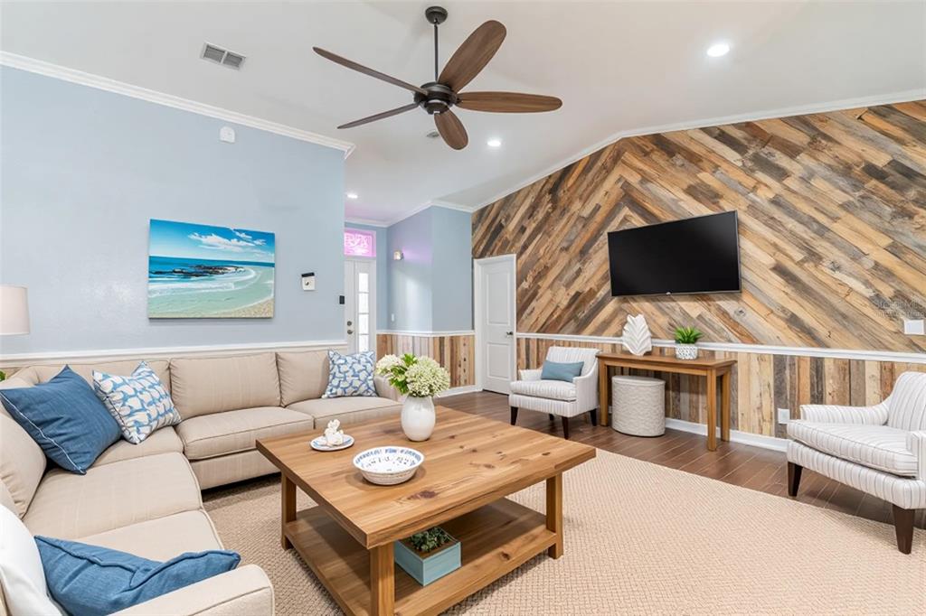A living room features a herringbone wood accent wall, a sectional sofa, and a ceiling fan — 109 REBECCA DRIVE NE, WINTER HAVEN, FL