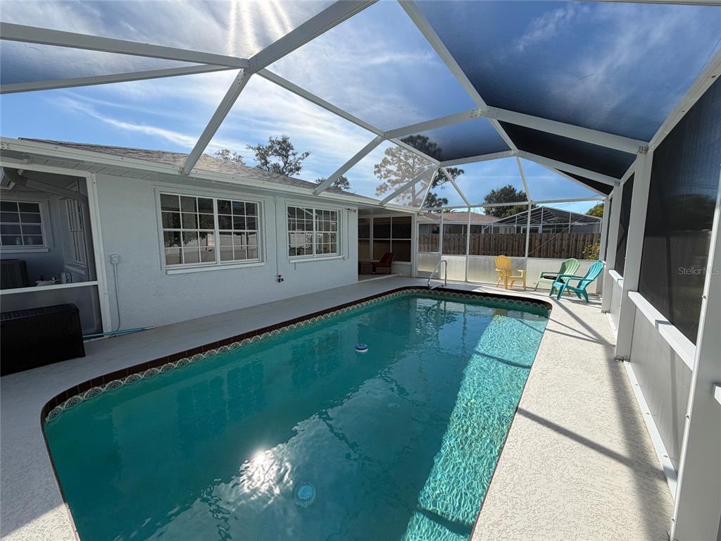A swimming pool is enclosed by a screened lanai attached to the back of a house — 1536 PORPOISE ROAD, VENICE, FL