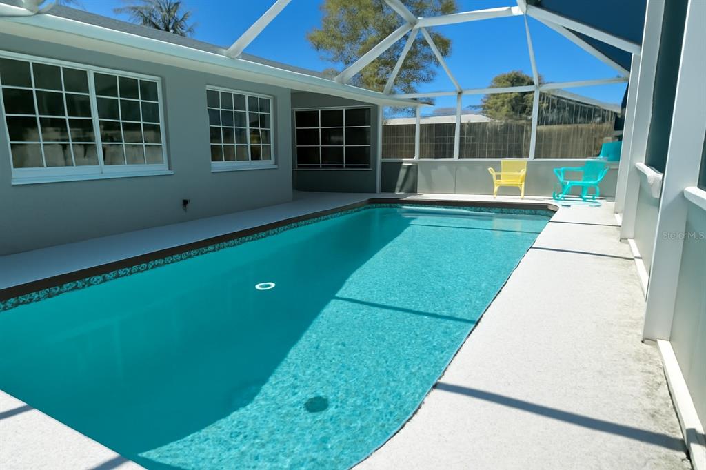 A rectangular swimming pool sits on a concrete patio enclosed by a screened-in lanai — 1536 PORPOISE ROAD, VENICE, FL