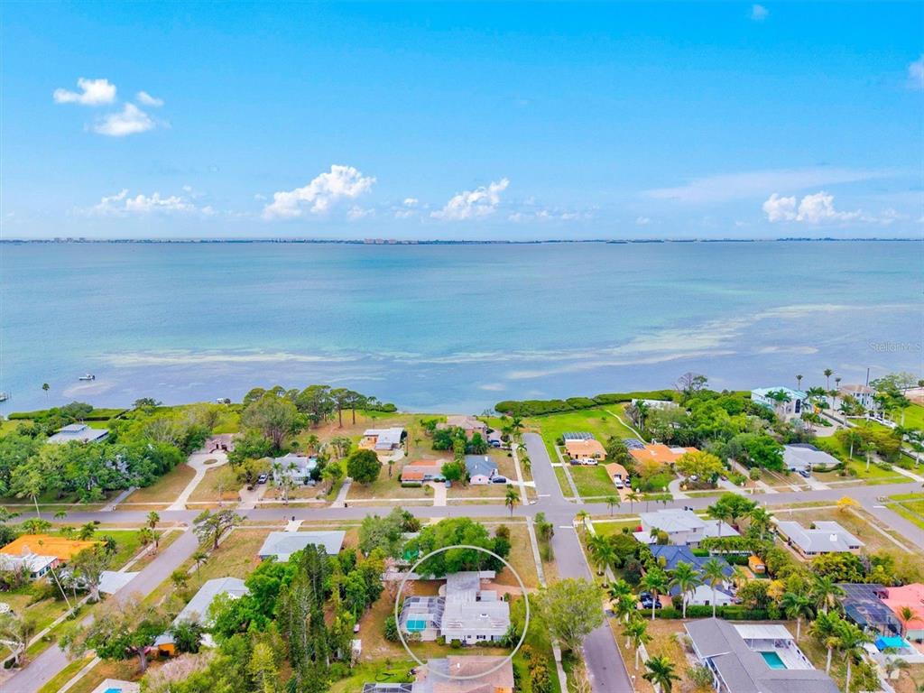 An aerial view shows a residential house with a pool, circled, near a large body water — 214 GAINES AVENUE, SARASOTA, FL