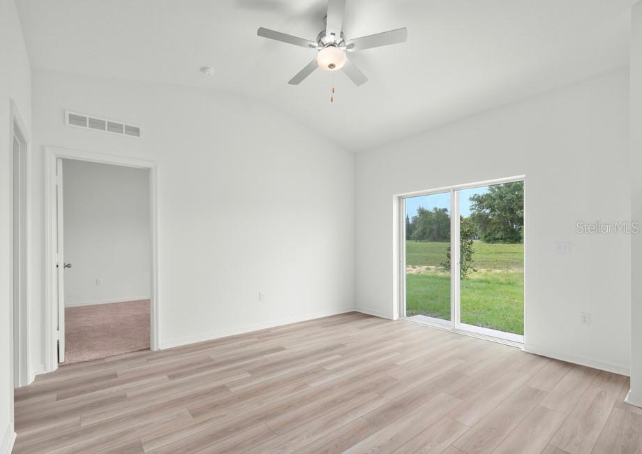 An empty room with light wood-look flooring, a ceiling fan, and sliding glass doors — 632 TANGELO TERRACE, BABSON PARK, FL