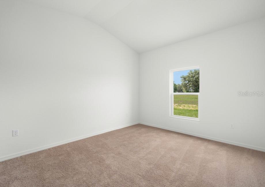 An empty bedroom features white walls, tan carpeting, and a single window overlooking a field — 632 TANGELO TERRACE, BABSON PARK, FL
