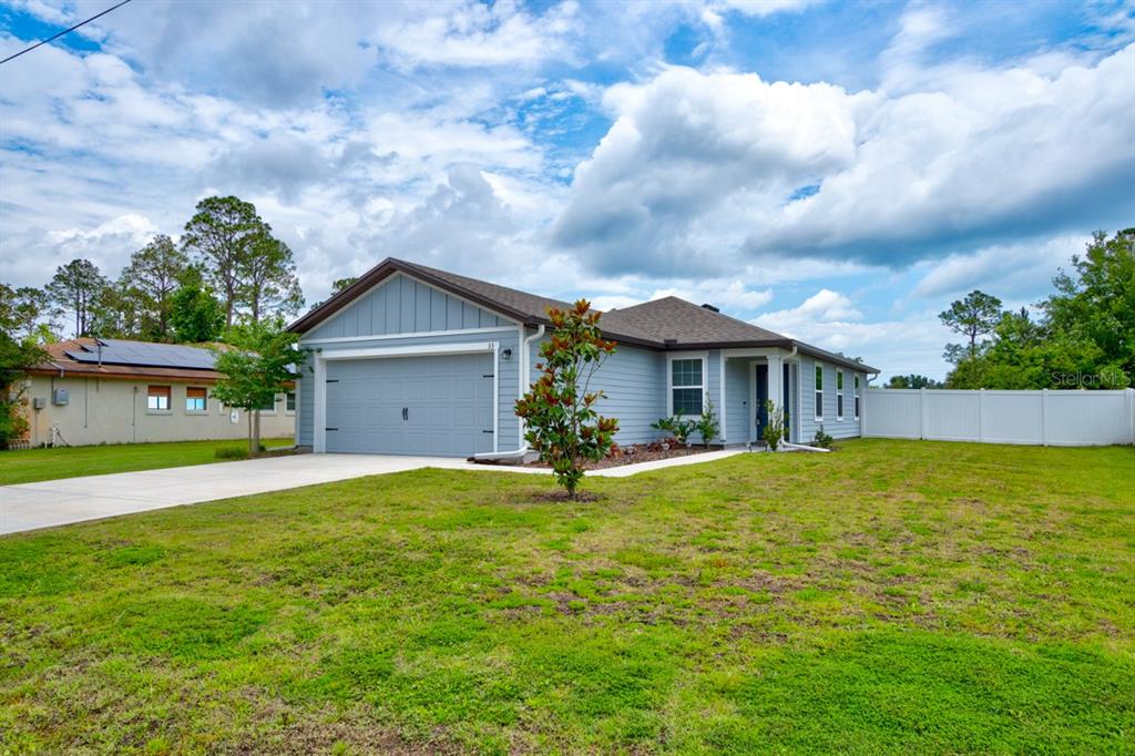 A light blue, single-story house with a two-car garage and a white vinyl fence — 33 PINE CROFT LANE, PALM COAST, FL