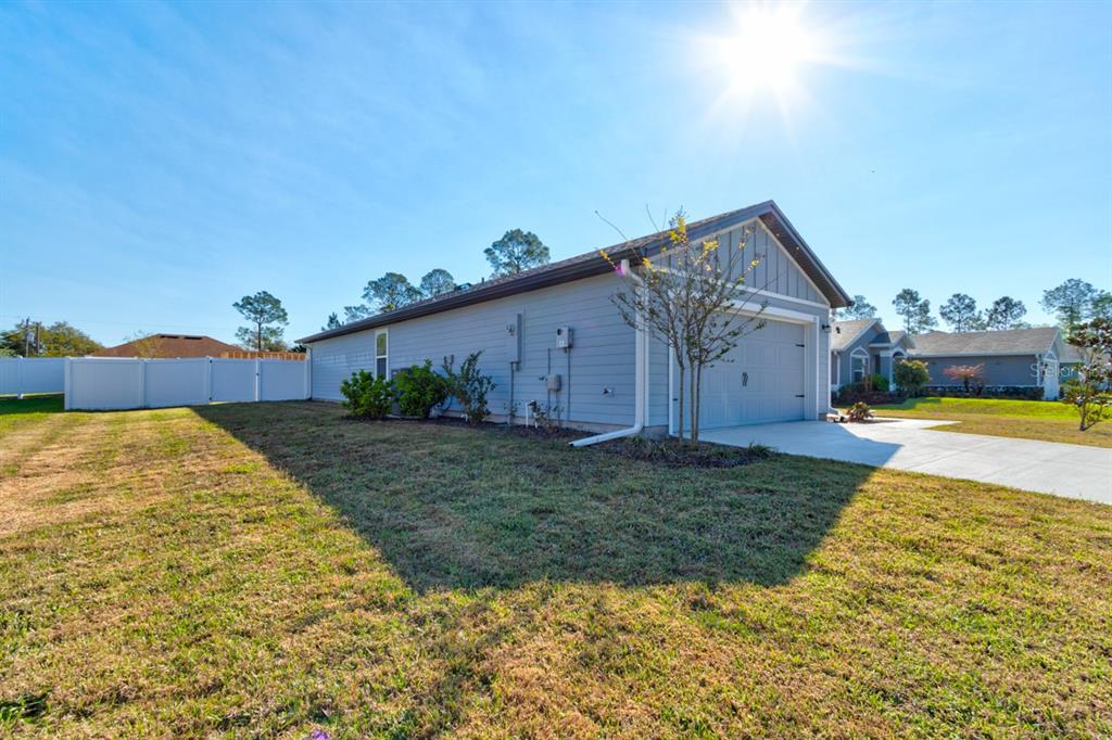 A side view of a light blue house with a garage and a grassy yard — 33 PINE CROFT LANE, PALM COAST, FL