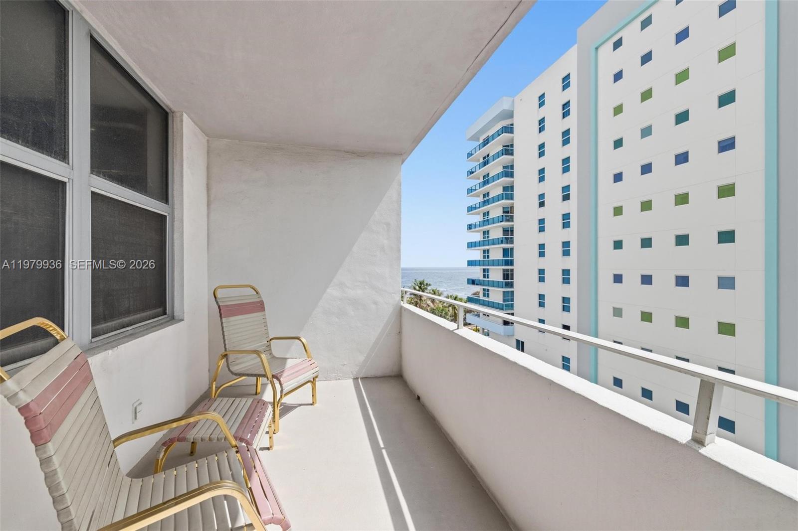 A balcony with two chairs overlooks the ocean and a neighboring high-rise building — 9225 Collins Ave # 610, Surfside FL 33154, SURFSIDE, FL