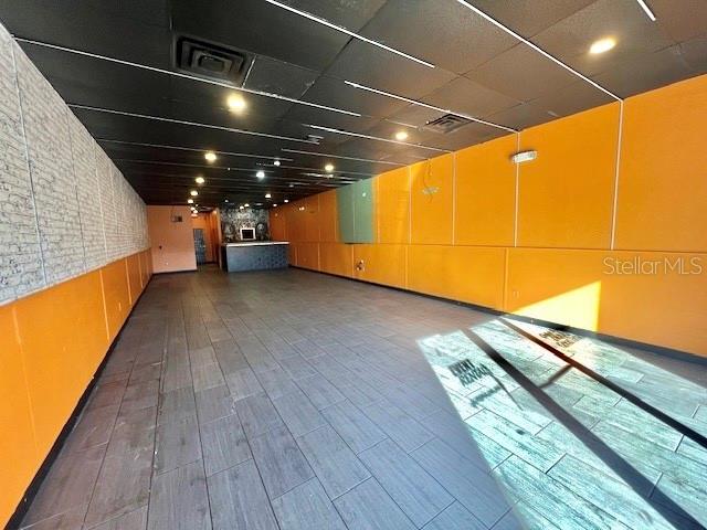An empty commercial space features orange walls, a black drop ceiling, and wood-look tile flooring — 3900 S GOLDENROD ROAD UNIT 118, ORLANDO, FL
