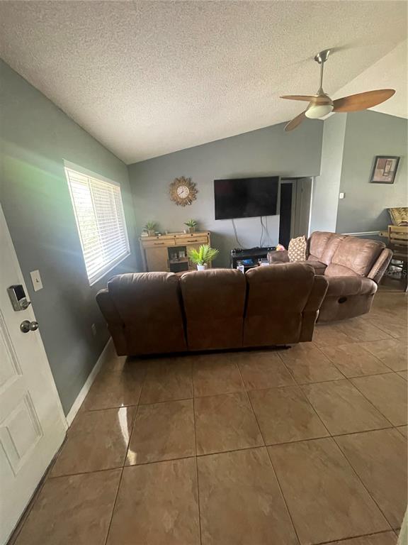 A living room features brown leather sofas, tile flooring, a ceiling fan, and a television — 6801 COMPASS COURT, ORLANDO, FL